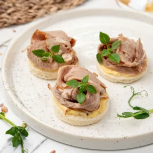 Häppchen mit gekochtem Schweinefleisch und eingelegter Gurke